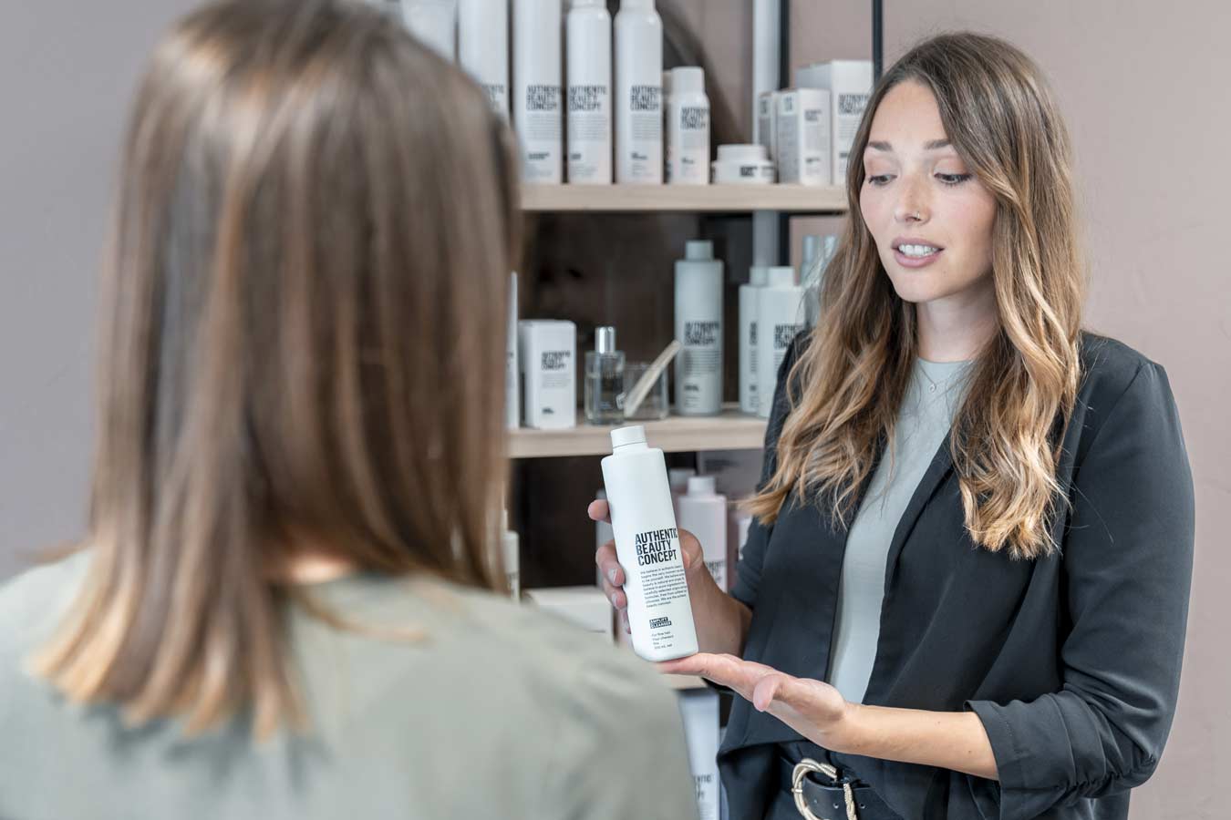 Coiffeuse verkauft einer Kundin ein Kosmetikprodukt